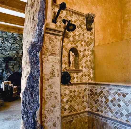 The master suite features a shower bordered by a dramatic log found nearby. James rescued the granite trim from a fabricator’s pile.